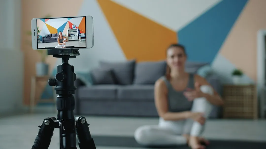Woman recording fitness video on phone with tripod.