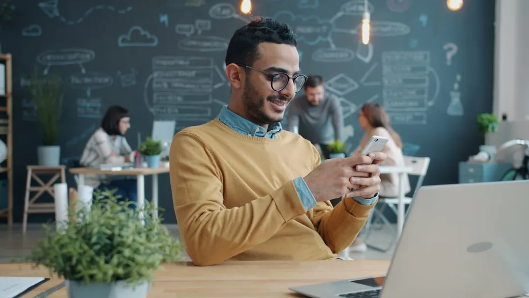 Man smiling while looking at his phone in office