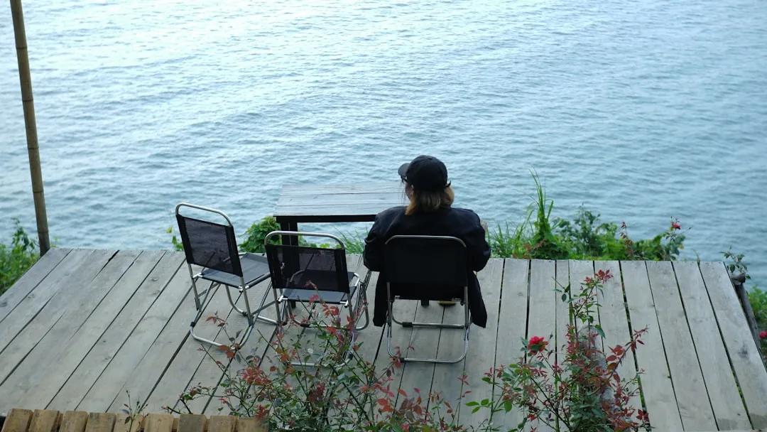 a woman sitting at a table on top of a wooden deck