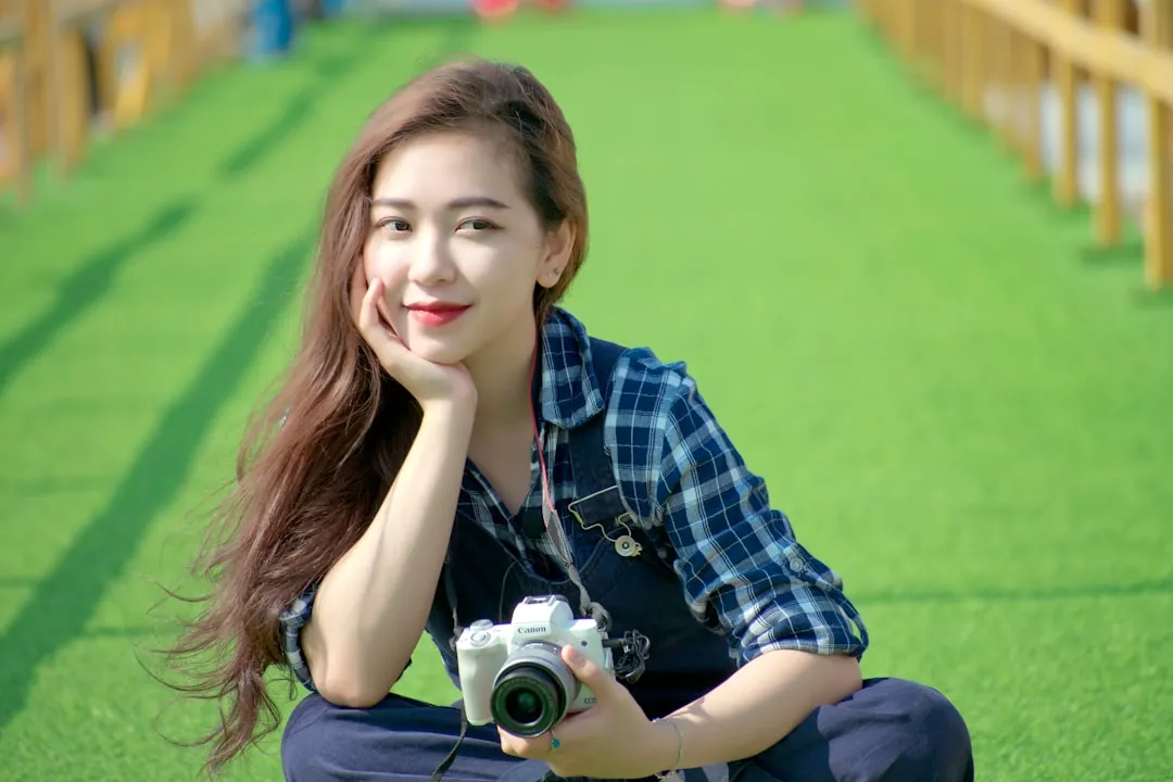 woman in blue and white plaid dress shirt holding camera
